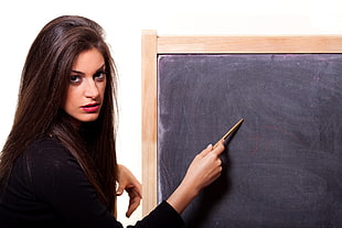 woman holding brown stick on black board