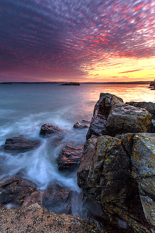 HDR photography of ocean beside rock boulders during yellow sunset HD wallpaper