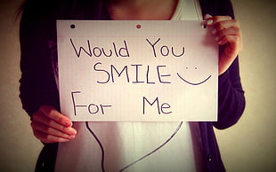 person holding paper with Would you smile for me print