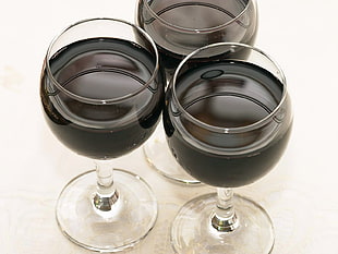 three black liquids on clear glass goblets