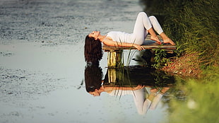 woman lying on stone above water