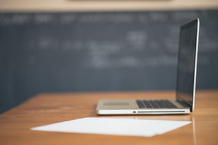 beige laptop on brown wooden table