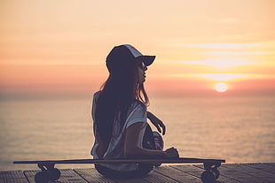 woman in white short and black cap standing with sunset background