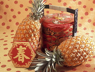 two peeled pineapples and red floral jar