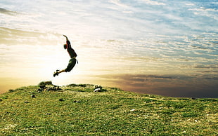silhouette of am man jumping on green fields during daytime HD wallpaper