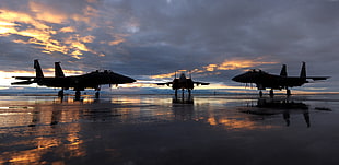 silhouette of three airplanes about to land under cloudy sky during sundown