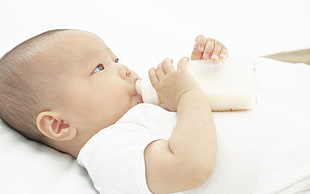 baby lying while bottle feeding at daytime HD wallpaper