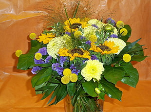 yellow and purple petaled flower bouquet on top of orange textile