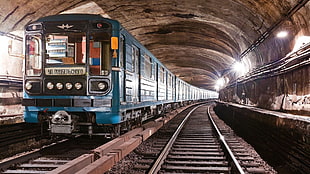 blue train inside the tunnel with lights and train rail