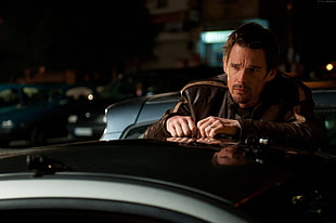 man wearing black leather jacket standing near black car movie character