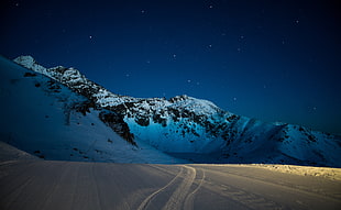 snow covered mountain near desert under starry night