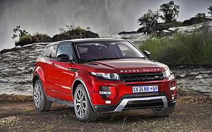 red Land Rover Range Rover SUV on brown soil at daytime