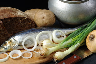 silver fish on chopping board with sliced onions