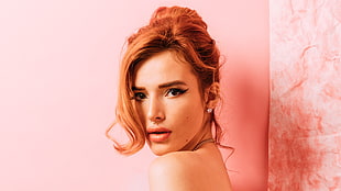 woman with orange hair standing beside pink wall