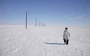 man walking on snow near post