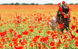 woman wearing red floral headdress in red flower field