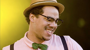 man wearing pink top. brown wicker hat and eyeglasses