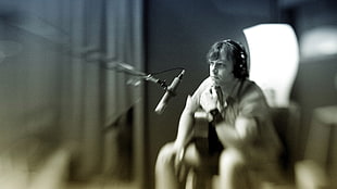 selective focus photography of man sitting beside microphone