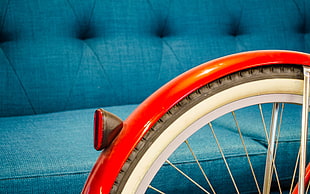 silver bike rim with tire and red bike taillight beside tufted teal fabric sofa