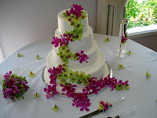 vanilla 4-tier fondant cake near two champagne flute glasses both on white fabric table cloth