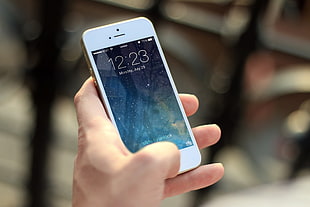 person holding a white iPhone 5