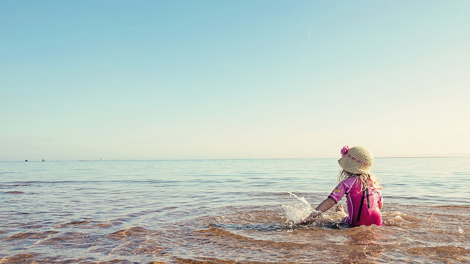 girl in pink shirt and brown sun hat on seashore HD wallpaper