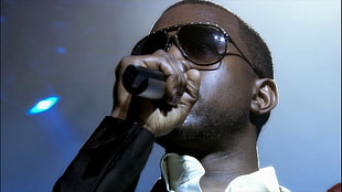 man wearing sunglasses holding microphone