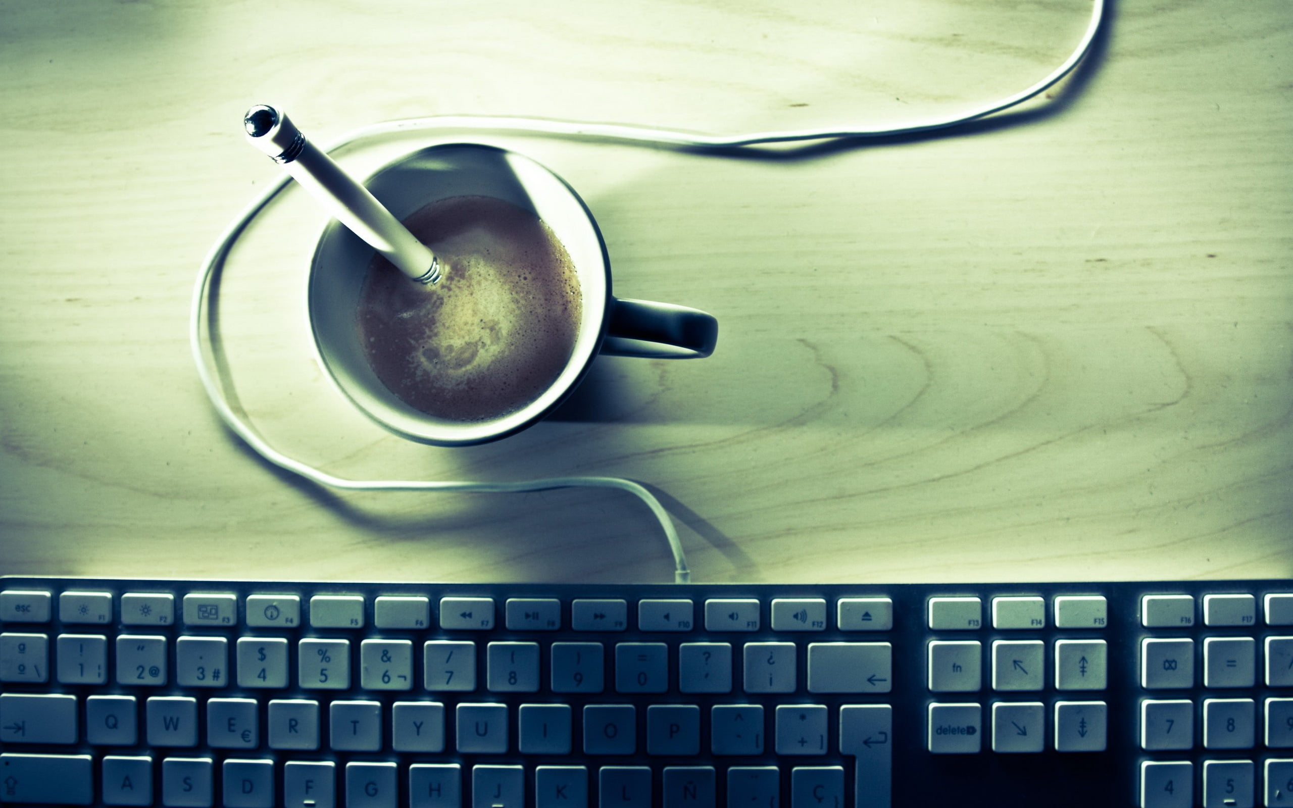 black ceramic mug filled with coffee near corded computer keyboard