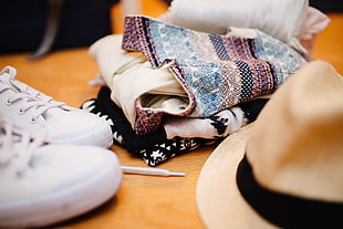 brown hat near pair of white sneakers and textiles