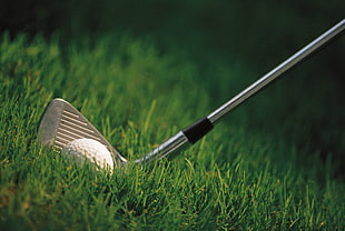 titanium golf wedge beside white golf ball
