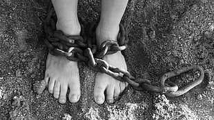 human feet with black metal chain  grayscale photo