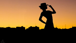 silhouette of woman holding hat while standing