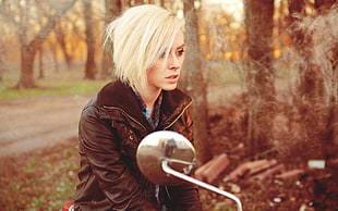 woman wearing black zip-up jacket sitting on motorcycle