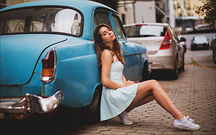 woman wearing blue dress leaning on blue car