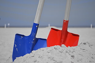 close up photo of two blue and red shovels