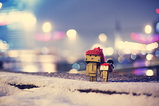 bokeh photography of two wooden figurines on concrete pavement