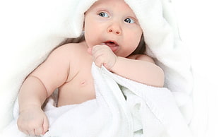 baby covered by white swaddle