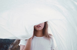 woman wearing white crew-neck T-shirt covered by white blanket