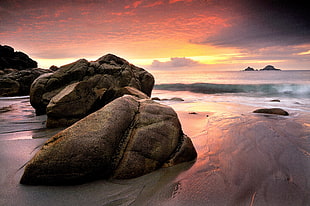 rock formation near wavy sea at sunset