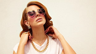 woman in white shirt with gold chain necklace and purple heart sunglasses
