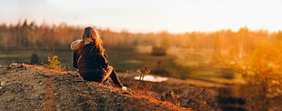 woman in parka jacket sitting during sunset HD wallpaper