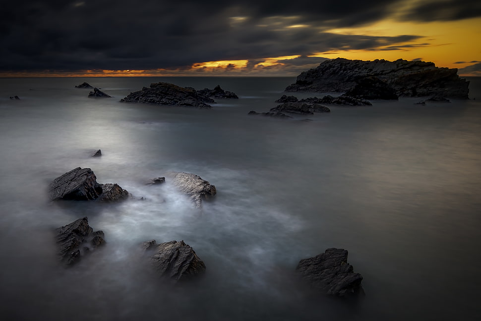 landscape photography of rocks in middle of sea under cloudy sky during daytime HD wallpaper