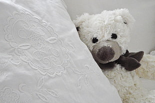 white bear plush toy beside white pillow