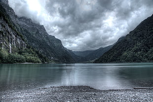 lake between the mountain during cloudy day