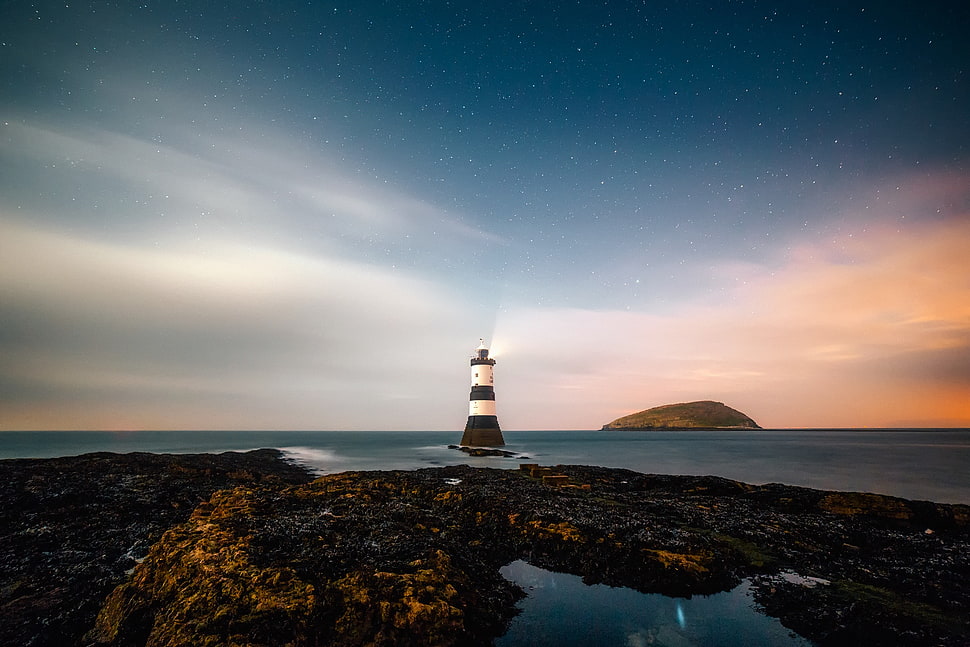 white and black Lighthouse in the middle of the ocean HD wallpaper