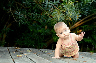 baby crawling on brown wooden pallet