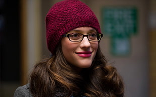 woman wearing maroon knit hat and black framed eyeglasses