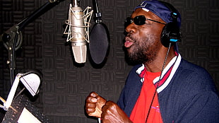 man singing on grey condenser microphone with black pop filter