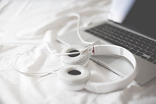 white corded headphones on top of gray laptop computer