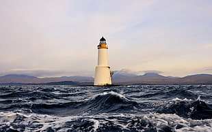 white concrete lighthouse beside body of water during daytime
